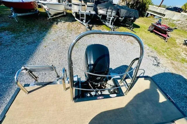 Slide: The Image of 2021 Harris 250 Cruiser pontoon boat with outboard motor, parked on gravel lot. - 12