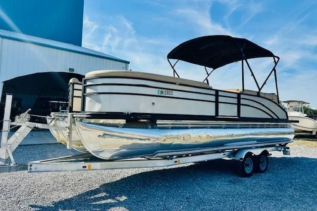 Slide: The Image of 2021 Harris 250 Cruiser pontoon boat on trailer, parked outdoors under blue sky. - 5