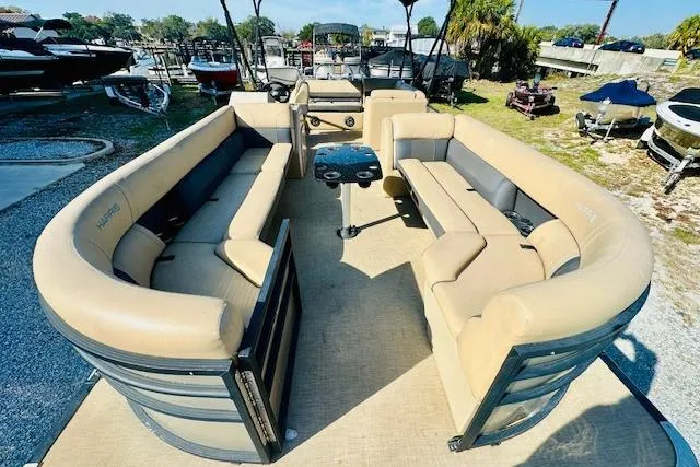 Slide: The Image of 2021 Harris 250 Cruiser pontoon boat with spacious seating and central table, docked outdoors. - 7