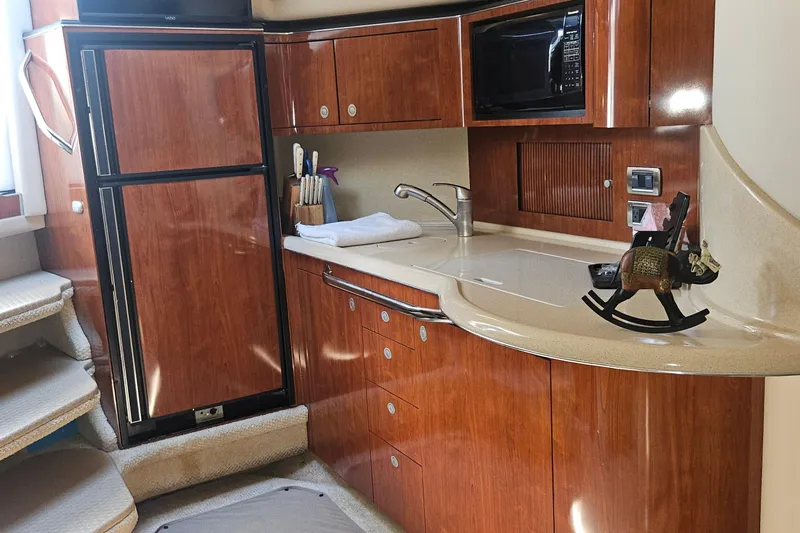 Slide: The Image of 2004 Sea Ray 380 Sundancer yacht interior with kitchenette, featuring wood cabinetry and modern appliances. - 12