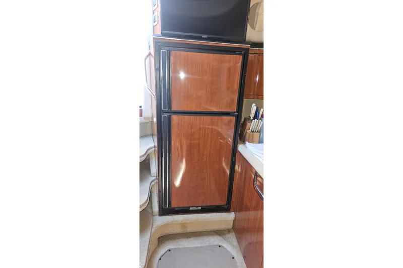 Slide: The Image of 2004 Sea Ray 380 Sundancer interior with wooden cabinetry and compact refrigerator. - 13