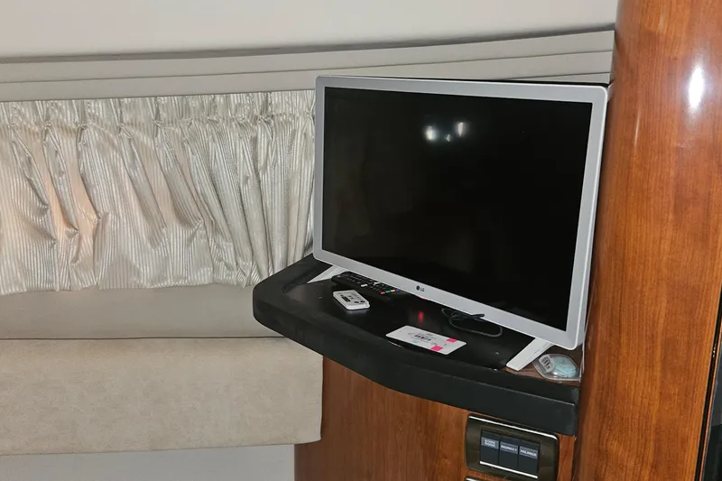 Slide: The Image of Interior of 2004 Sea Ray 380 Sundancer with TV and remote on wooden shelf. - 23