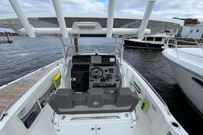 Slide: The Image of 2023 Jeanneau Leader 9.0 CC boat cockpit with steering wheel and controls, docked by the water. - 3