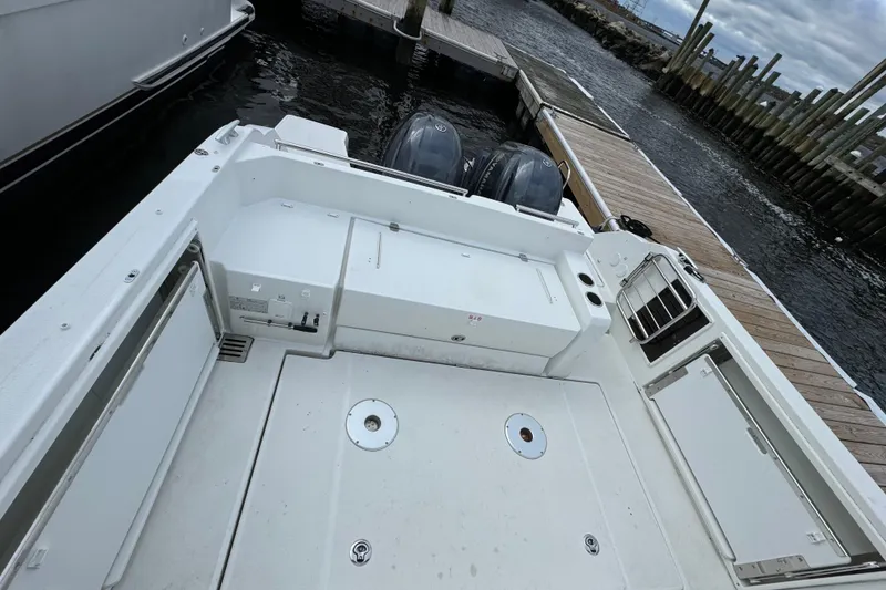 Slide: The Image of 2023 Jeanneau Leader 9.0 CC boat docked, showcasing spacious deck and dual outboard engines. - 5