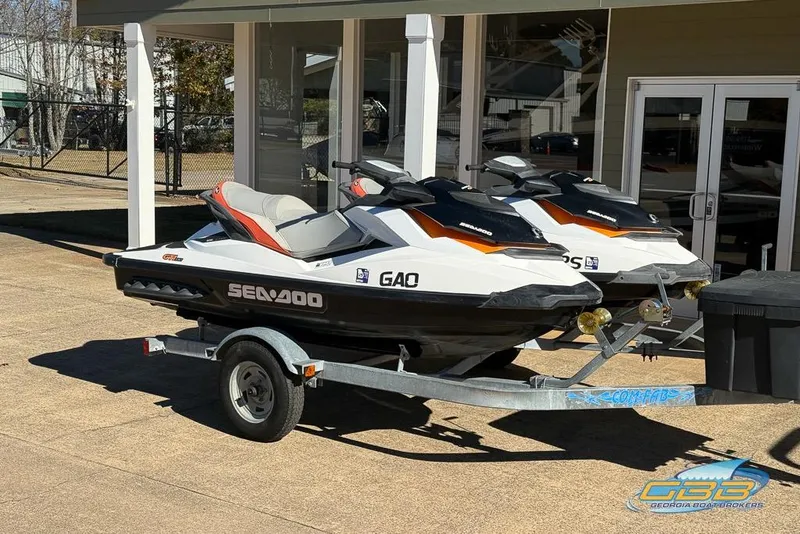 The Image of 2011 Sea-Doo GTI 130 jet skis on trailer outside a building. - 0