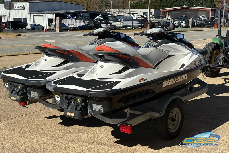 Slide: The Image of Two 2011 Sea-Doo GTI 130 jet skis on a trailer, parked outdoors. - 10