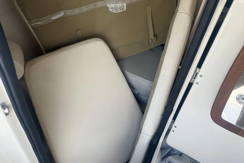Slide: The Image of 2023 Grady-White Freedom 215 interior cabin with beige cushions and storage area. - 12