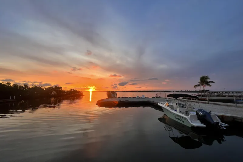 Slide: The Image of 2023 Grady-White Freedom 215 boat docked at sunset, calm waters, vibrant sky. - 8