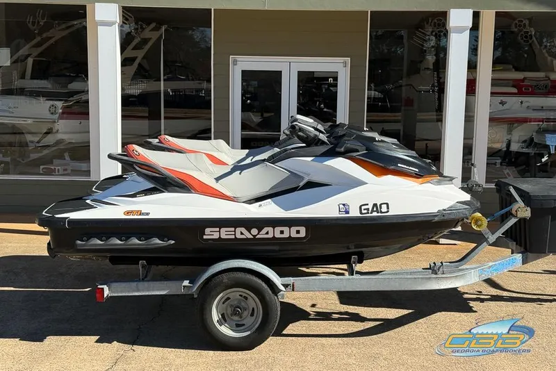 Slide: The Image of 2012 Sea-Doo GTI 130 jet ski on trailer, parked outside a showroom. - 2