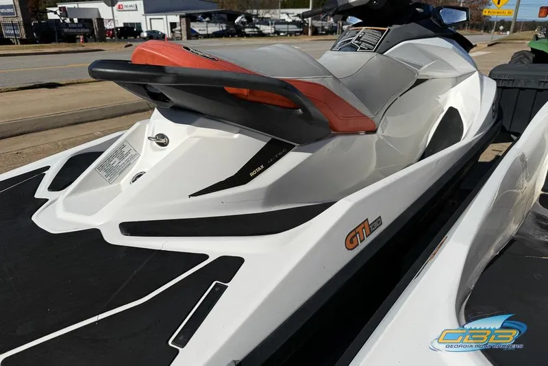 Slide: The Image of 2012 Sea-Doo GTI 130 jet ski, white with orange accents, parked on trailer. - 6