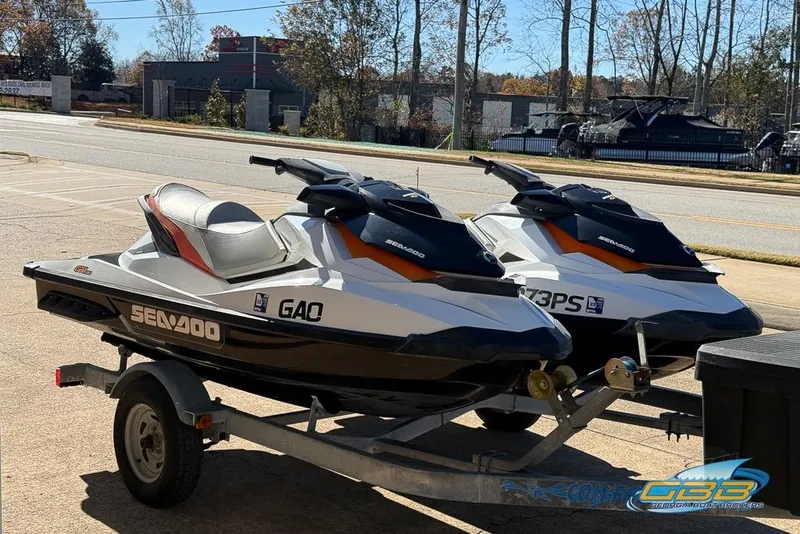 Slide: The Image of Two 2012 Sea-Doo GTI 130 jet skis on a trailer in a parking lot. - 9
