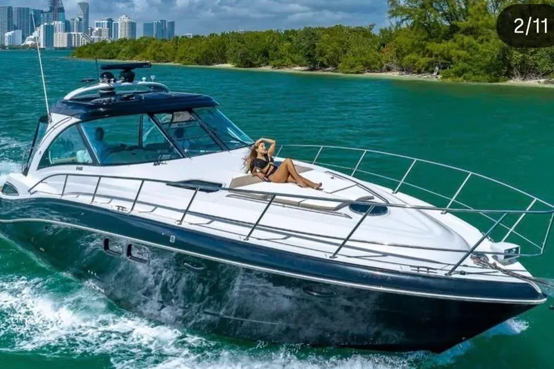 Slide: The Image of 2009 Four Winns V458 yacht cruising in turquoise waters near a city skyline. - 1