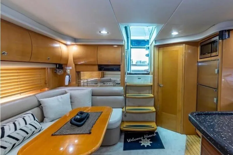 Slide: The Image of 2009 Four Winns V458 yacht interior with cozy seating, wooden cabinetry, and stairs leading to deck. - 10