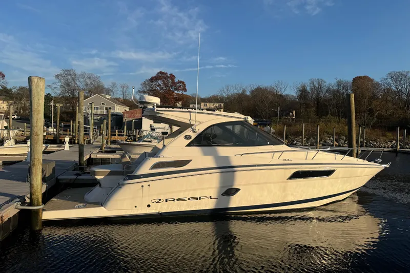 The Image of 2017 Regal 35 Sport Coupe docked at a marina under a clear blue sky. - 0