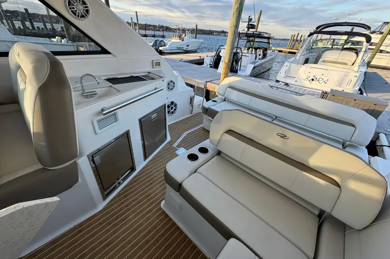Slide: The Image of 2017 Regal 35 Sport Coupe interior with seating, kitchenette, and docked boats in background. - 6