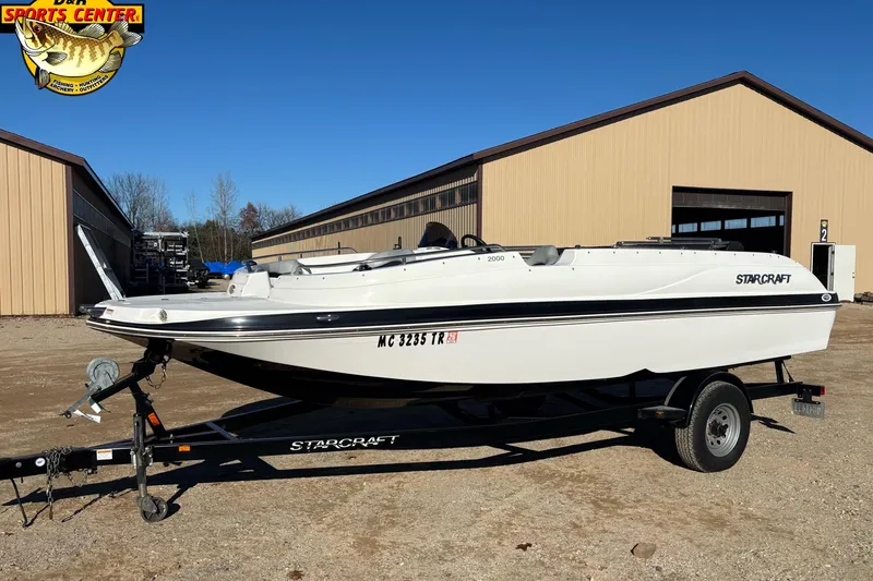 The Image of 2014 Starcraft 2000 IO Limited boat on trailer outside a sports center. - 0