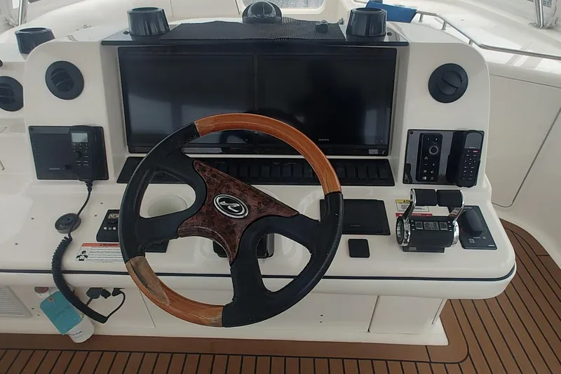 Slide: The Image of 2007 Sea Ray 58 Sedan Bridge helm with dual screens and wooden steering wheel. - 14