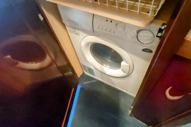 Slide: The Image of Laundry area inside 2007 Sea Ray 58 Sedan Bridge yacht, featuring a compact washing machine. - 29