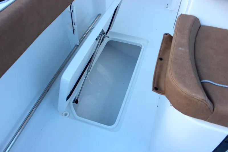 Slide: The Image of 2026 Sea Hunt Gamefish 28 Forward Seating storage compartment with brown cushioned seat. - 12