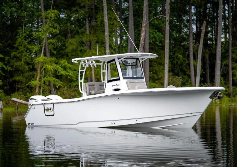 Slide: The Image of Manufacturer Provided Image: 2026 Sea Hunt Gamefish 28 Forward Seating boat on calm water, surrounded by trees. - 76