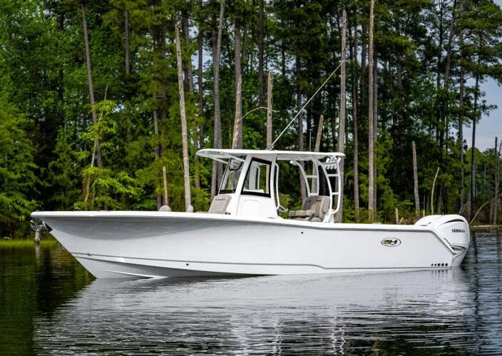 Slide: The Image of Manufacturer Provided Image: 2026 Sea Hunt Gamefish 28 boat on calm water, surrounded by lush trees. - 79