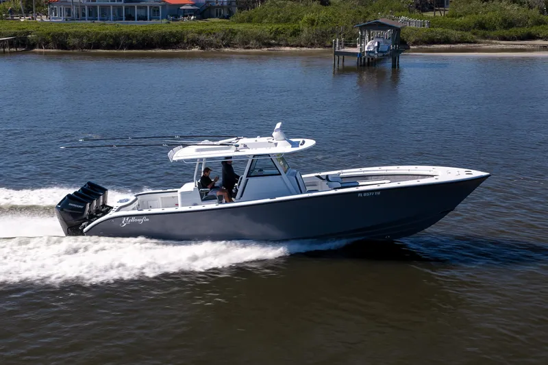 Slide: The Image of 2024 Yellowfin 39 Offshore boat cruising on a calm river near a dock. - 14