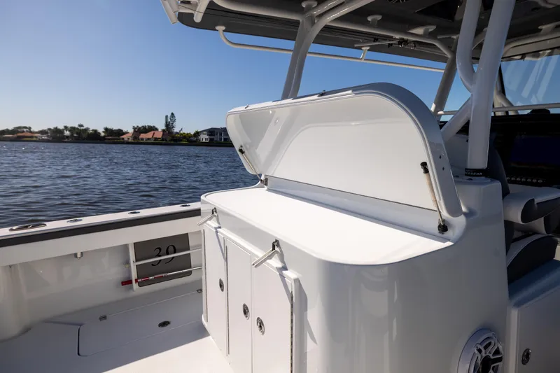 Slide: The Image of 2024 Yellowfin 39 Offshore boat interior with open storage compartment, overlooking calm waters. - 49