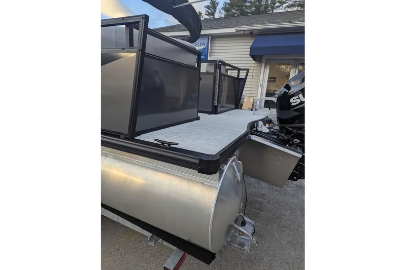 Slide: The Image of 2026 Dockside 22DQ pontoon boat with Suzuki outboard motor, docked near a building. - 6