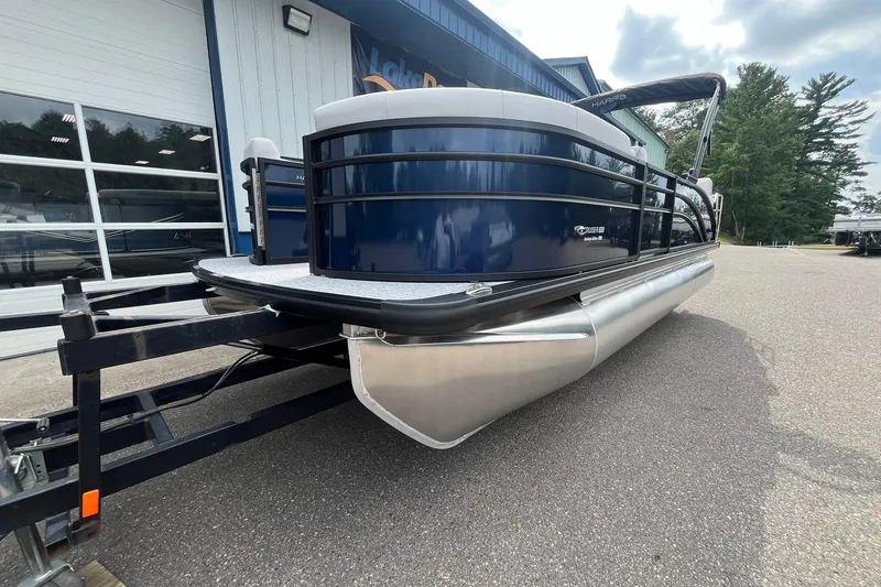 Slide: The Image of 2026 Harris Cruiser 210 pontoon boat on trailer, parked outside a building. - 6