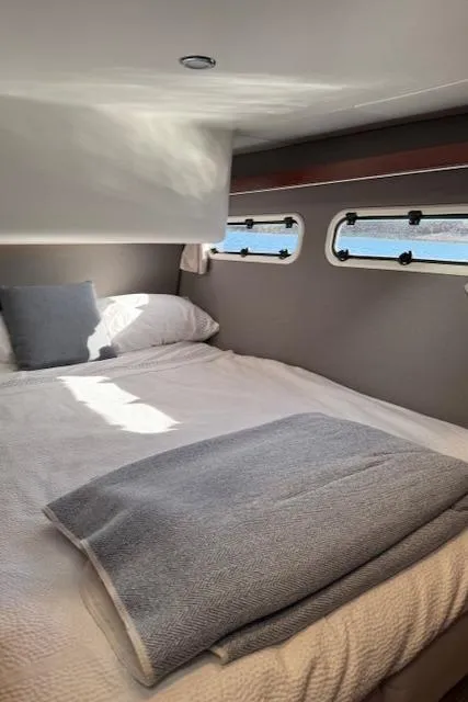 Slide: The Image of Die Kabine der Nimbus 405 Coupe 2024 zeigt ein gemütliches Bett mit Fenstern, die auf das Wasser blicken. - 23