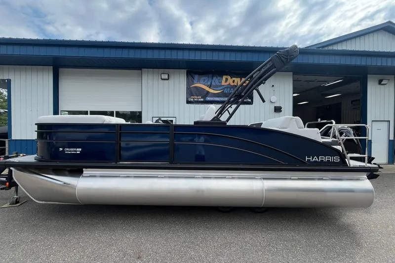 The Image of 2026 Harris Cruiser 210 pontoon boat parked outside a marine dealership. - 1