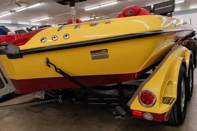 Slide: The Image of 2008 Ranger Z520 Comanche boat in vibrant yellow and red, displayed indoors. - 14
