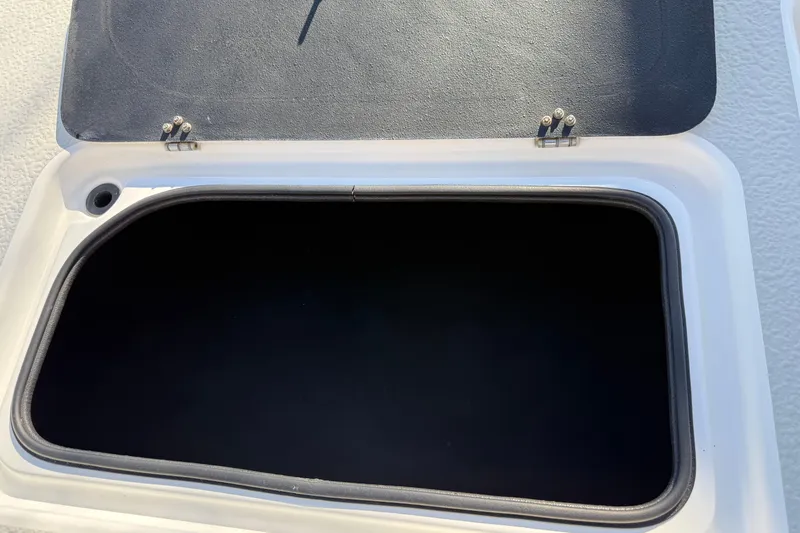 Slide: The Image of Open storage compartment on 2018 SCB Recon boat, featuring a black interior and secure hinges. - 44