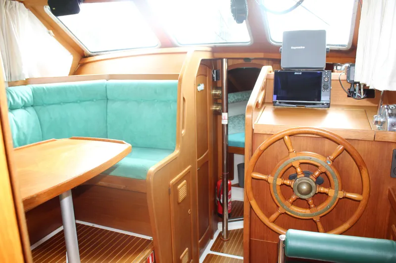 Slide: The Image of Interior of 1998 Nauticat 32 Pilothouse with wooden helm and green seating. - 11