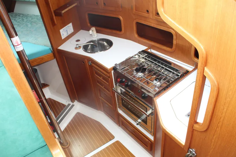 Slide: The Image of 1998 Nauticat 32 Pilothouse interior kitchen with stove, sink, and wooden cabinetry. - 20