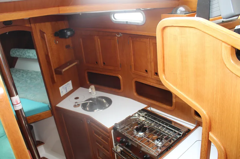 Slide: The Image of 1998 Nauticat 32 Pilothouse interior with wooden cabinetry, compact kitchen, and cozy sleeping area. - 21