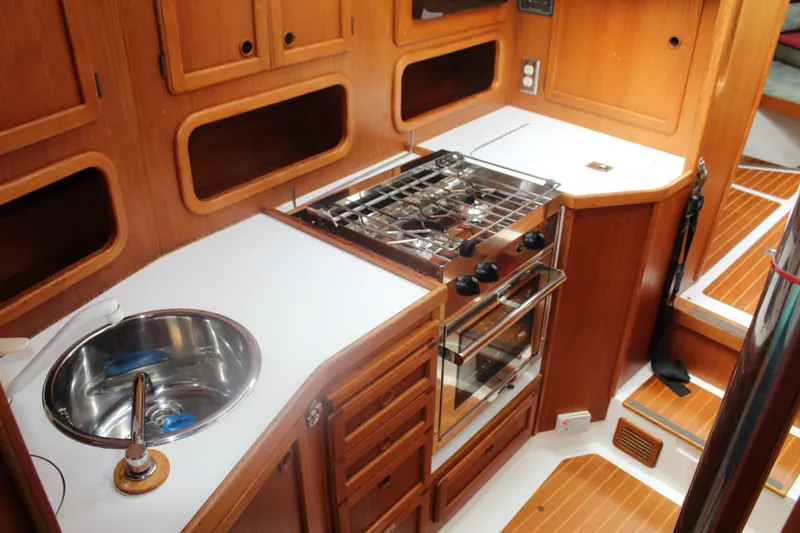 Slide: The Image of 1998 Nauticat 32 Pilothouse kitchen with wooden cabinetry, stainless steel sink, and stove. - 27