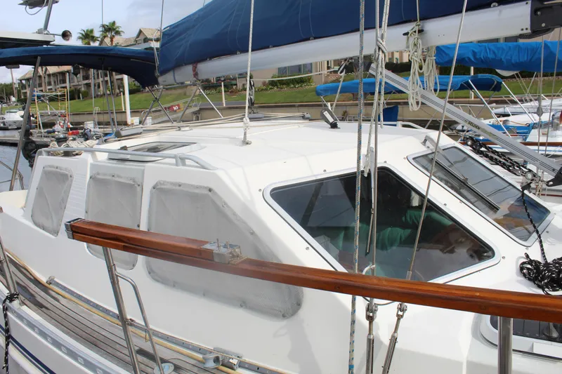 Slide: The Image of 1998 Nauticat 32 Pilothouse sailboat docked, featuring a sleek white cabin and blue sail. - 4