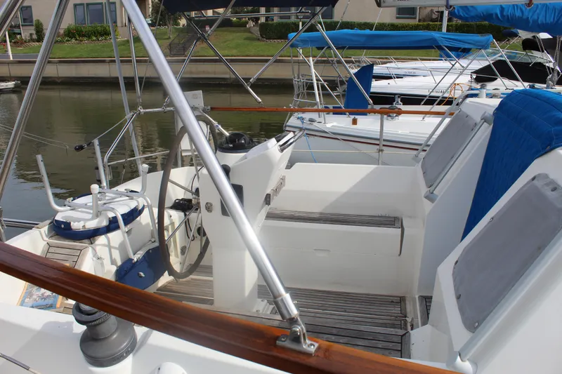 Slide: The Image of 1998 Nauticat 32 Pilothouse sailboat cockpit with steering wheel and seating, docked by the water. - 5