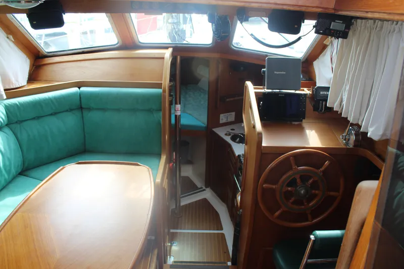 Slide: The Image of Interior of 1998 Nauticat 32 Pilothouse with wooden helm and teal seating. - 6