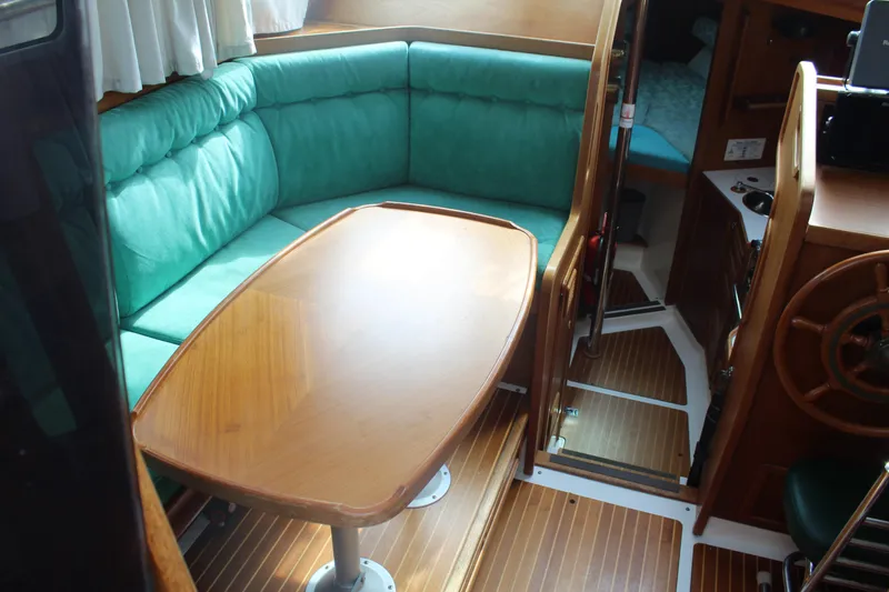 Slide: The Image of 1998 Nauticat 32 Pilothouse interior with green seating and wooden table. - 7