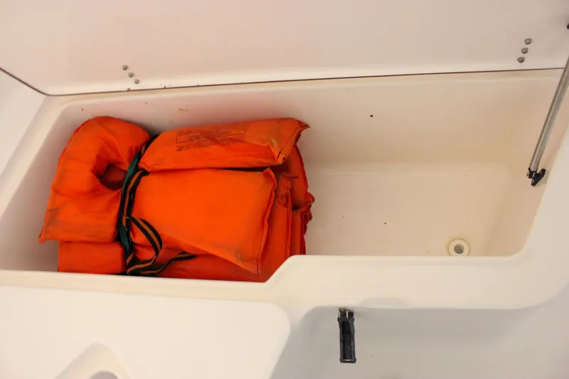 Slide: The Image of Storage compartment with orange life jackets on a 2006 Sea Hunt Triton 207 boat. - 14