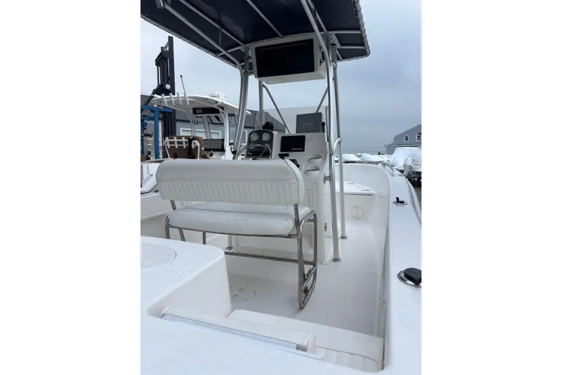 Slide: The Image of 2006 Sea Hunt Triton 207 boat interior with helm and seating, docked outdoors. - 21