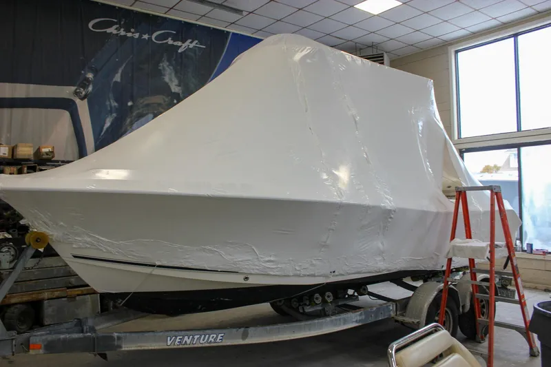 Slide: The Image of 2006 Sea Hunt Triton 207 boat covered in protective wrap inside a workshop. - 30