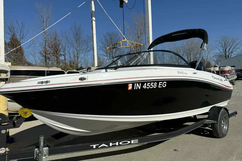 The Image of 2021 Tahoe 550 TS boat on trailer, black and white design, parked outdoors. - 0