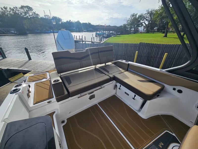 Slide: The Image of 2025 Monterey Elite 27 OB boat interior with seating, docked by a scenic waterfront. - 44