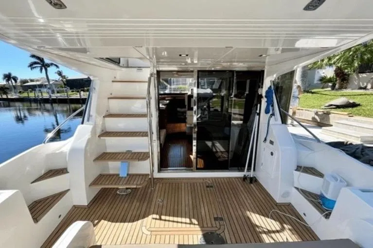 Slide: The Image of 2017 Galeon 380 Fly yacht interior with wooden deck and stairs, docked by a serene waterfront. - 3