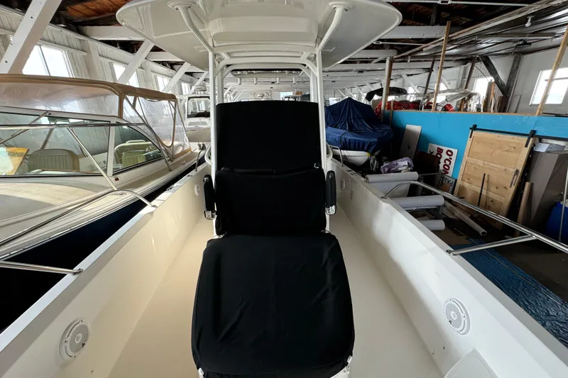 Slide: The Image of 2014 Boston Whaler 270 Dauntless boat interior in storage, featuring seating and canopy. - 15