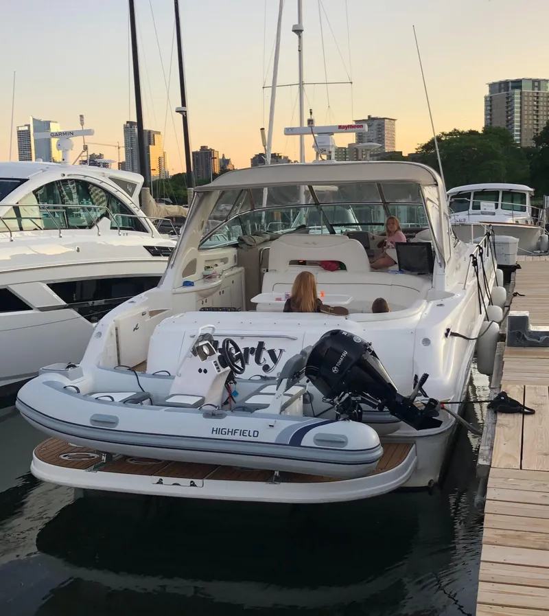 Slide: The Image of 2000 Sea Ray 460 Sundancer docked, featuring a Highfield tender, with city skyline in the background. - 5