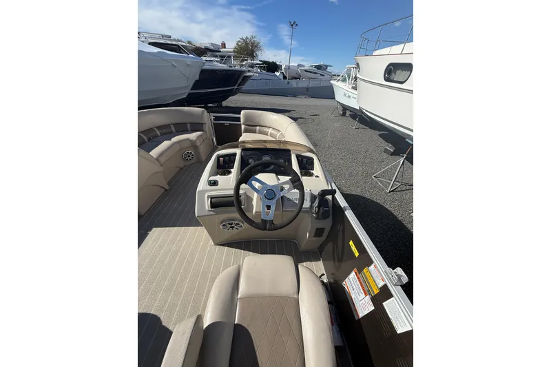 Slide: The Image of 2016 Bennington SX22 boat interior with steering wheel and seating, docked among other boats. - 10